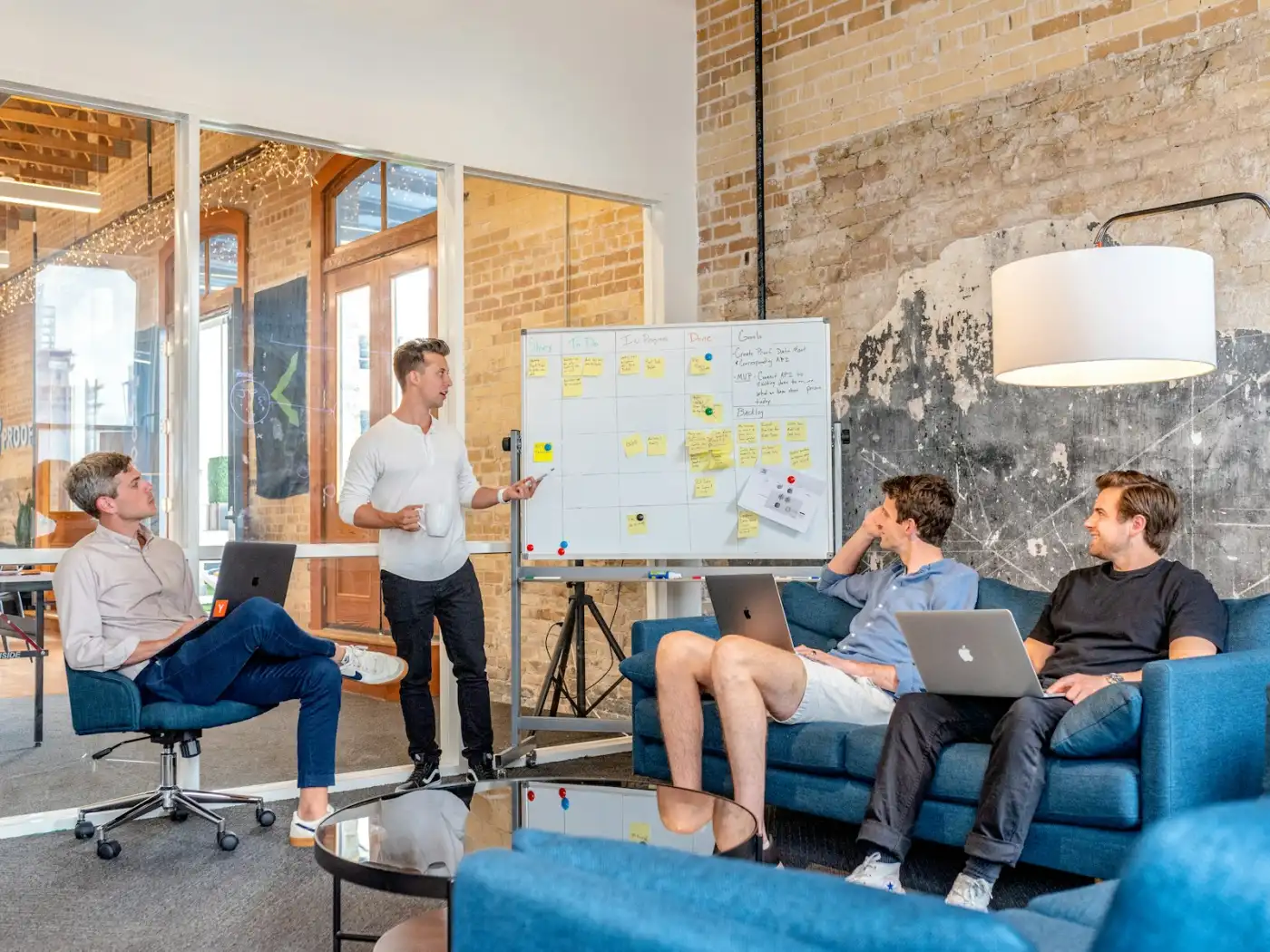 A product team in a whiteboard standup, talking through the board